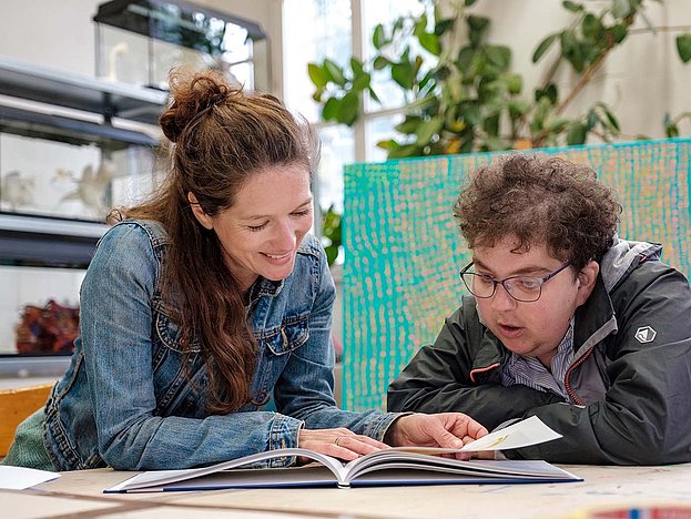 Zwei junge Frauen blättern in einer Bücherei in einem Buch