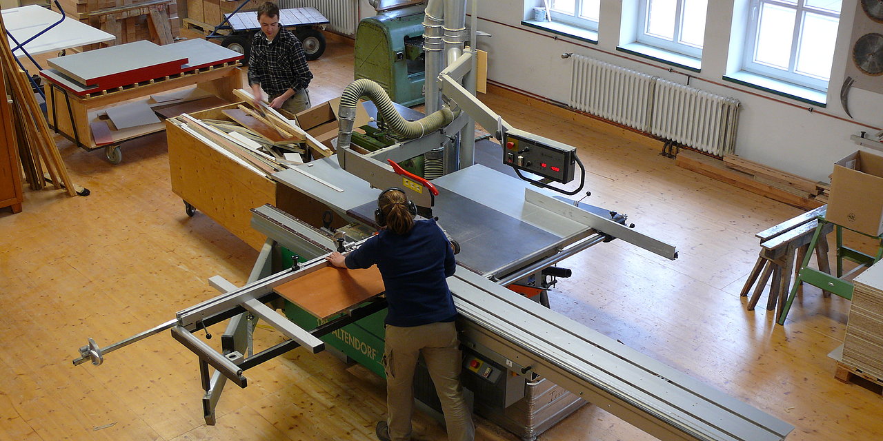 Ein Tischler arbeitet in einer Werkstatt an einer großen Kreissäge