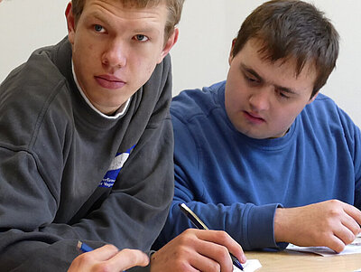 Vier junge Leute sitzen an einem Tisch und haben etwas zu schreiben dabei