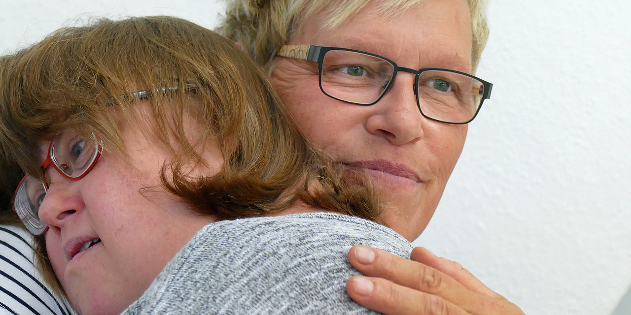 Zwei Frauen liegen sich in den Armen und lächeln