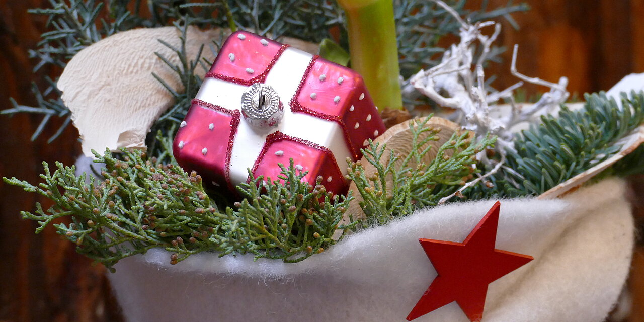 Eine Dekoration mit einer mit Tannenzweigen und roter Geschenkschachtel gefüllten Weihnachtsmütze