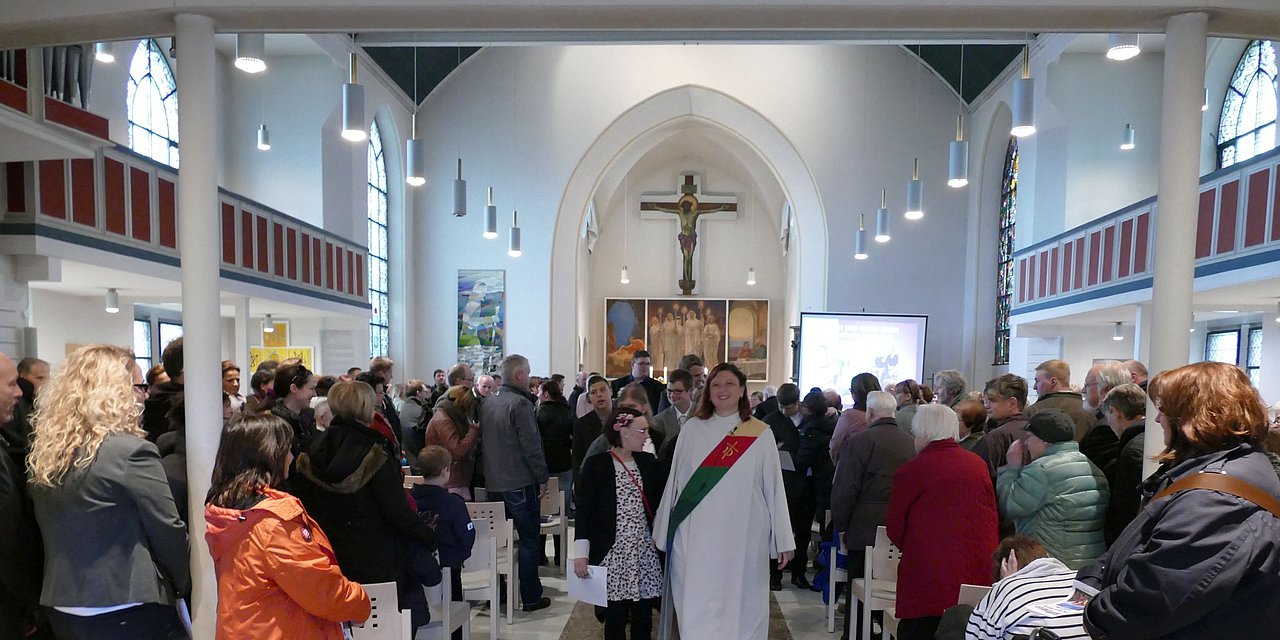 Eine volle Kirche, Menschen sind aufgestanden, andere ziehen feierlich durch den Gang hinaus 